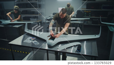 Focused Engineers Meticulously Installing Internal Components and Wiring Into Fuselage of Drone Focused Engineers Meticulously Installing Internal Components and Wiring Into Fuselage of Drone 133765029