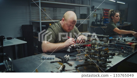 Busy, Well Lit Tech Workshop Shows Multiple Engineers Immersed in Drone Development 133765049