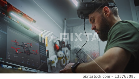 Bearded Man in Tactical Gear Deeply Focused, Using Computer Display and FPV Gear 133765093