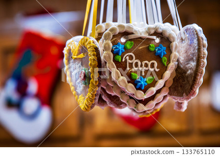 Gingerbread hert cookie decorated with floral details and the word Papa. Lebkuchenherz hanging at a german christmas market stall. Sentimental gift for occasions like father day, family celebrations Gingerbread hert cookie decorated with floral details and the word Papa. Lebkuchenherz hanging at a german christmas market stall. Sentimental gift for occasions like father day, family celebrations 133765110