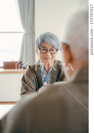 An elderly couple taking pictures of the scenery with their smartphones at a traditional Japanese inn 133765817