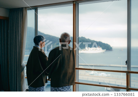 An elderly couple at a hotel looking at the scenery from the window An elderly couple at a hotel looking at the scenery from the window 133766081