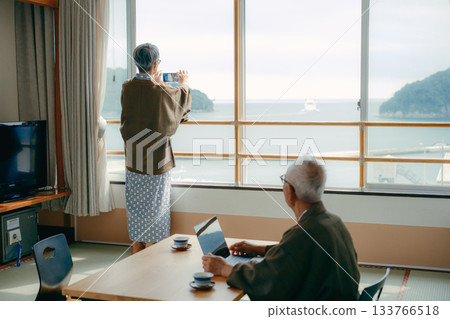 一對老年夫婦在傳統旅館的日式房間拍攝風景照。 133766518