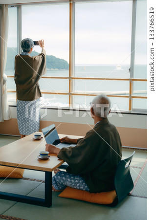 一對老年夫婦在傳統旅館的日式房間拍攝風景照。 133766519