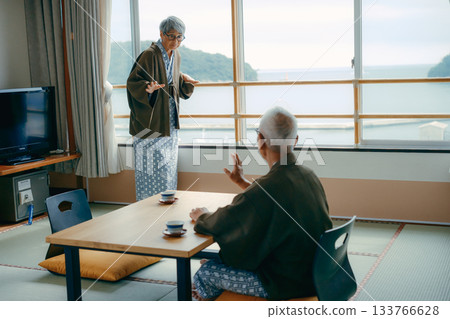 An inn scene with an elderly woman waving at the window and her husband watching over her. 133766628