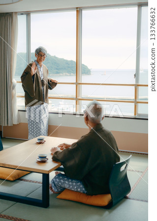 旅店裡的一幕：一位老婦人向窗外揮手，她的丈夫在一旁看著她。 133766632