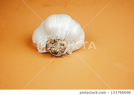 Fresh garlic bulbs and cloves on an orange background Fresh garlic bulbs and cloves on an orange background 133766696