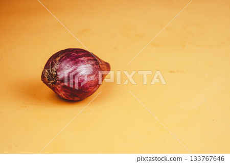 Single red onion on a vibrant orange background Single red onion on a vibrant orange background 133767646