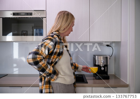woman preparing coffee with home espresso machine in bright modern kitchen woman preparing coffee with home espresso machine in bright modern kitchen 133767753
