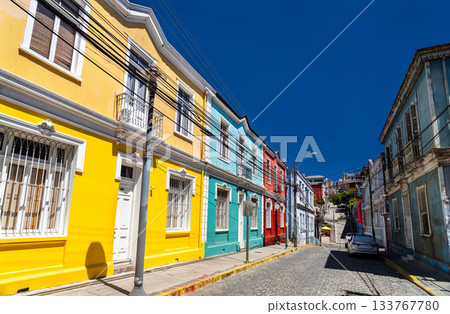 View of Templeman Street in between Cerro Concepcion and Cerro Alegre. Colorful historic houses line the steep cobblestone street under a deep blue sky 133767780