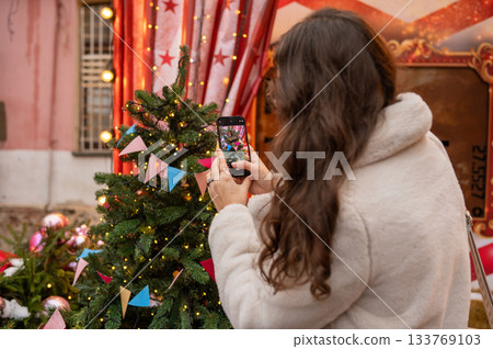 Female capturing festive christmas tree decorations outdoors 133769103