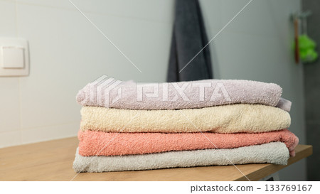 Stacked soft towels in bathroom setting on wooden surface Stacked soft towels in bathroom setting on wooden surface 133769167
