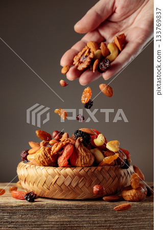 Mix of dried fruits is poured in a wicker bowl. Mix of dried fruits is poured in a wicker bowl. 133769837