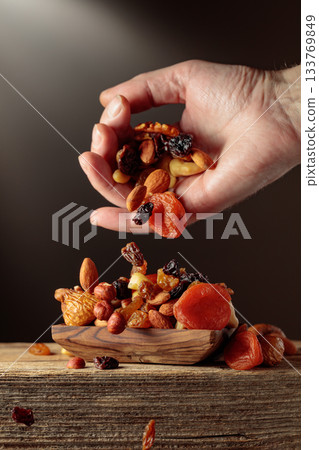 Mix of dried fruits is poured in a wooden dish. Mix of dried fruits is poured in a wooden dish. 133769849