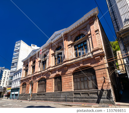 View of historic architecture on Prat Street in Valparaiso, Chile. The Civil Registry building and other classical structures line the street under a deep blue sky 133769851