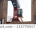 Close-up view of Control Cabin of Red-and-white Tower Crane on Construction Site against Blue Sky on Sunny Day. View through the Opening of Monolithic Box Window. 133770917
