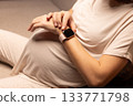 Pregnant woman with watches. Pregnant woman looking at her watches. 133771798