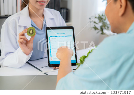 Close up nutritionist using tablet to explaining personalized meal plan with AI to patient. 133771917