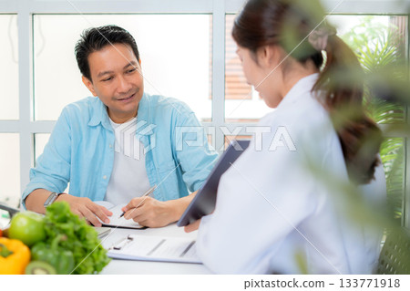 Asian nutritionist using tablet to explaining personalized meal plan with AI to patient. 133771918