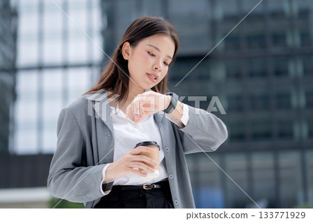 Young asian businesswoman in city talking to smartwatch using voice command with AI. 133771929