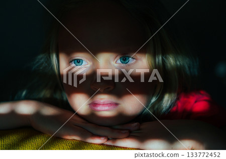 Child in Shadow Light with Thoughtful Expression 133772452