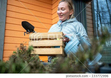 woman doing balcony gardening and cleaning tasks in autumn season 133772996