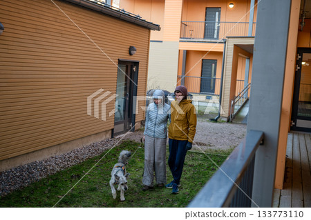 couple walking dog together in modern residential courtyard on cold autumn day 133773110