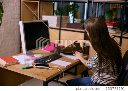 Young woman organizing documents and materials at office desk Young woman organizing documents and materials at office desk 133773291
