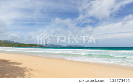 A serene beach scene featuring golden sand, turquoise waters, and gentle waves 133773495
