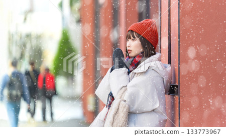 一位女子站在雪中的街角 133773967