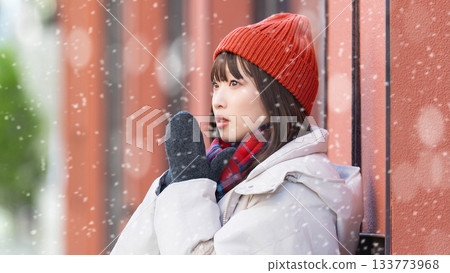 A woman standing on a street corner in snowy winter A woman standing on a street corner in snowy winter 133773968