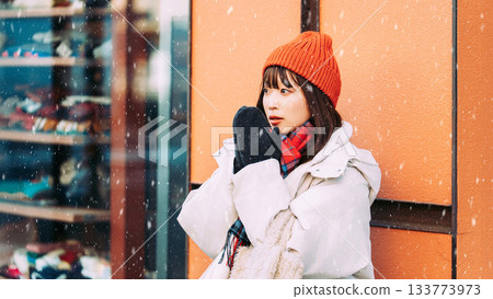 一位女子站在雪中的街角 133773973