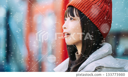 一位微笑的女子站在雪中的街角 133773980