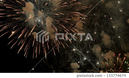 golden fireworks glow, nostalgic evening scene unfolds, oldfashioned color palette illuminates dark cityscape beautifully, celebratory bursts of color streak through darkness with warm vintage hues 133774674