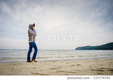 Woman walking on beach, autumn cold day Woman walking on beach, autumn cold day 133774705