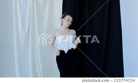 Professional model posing in a chic white top and black skirt against a striking black and white backdrop, embodying contemporary elegance and fashion forward style Professional model posing in a chic white top and black skirt against a striking black and white backdrop, embodying contemporary elegance and fashion forward style 133774724