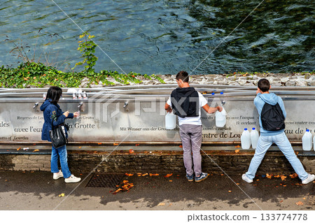 Pilgrims to the Sanctuary of Lourdes in France filling up bottle 133774778