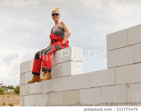 Woman in dungarees taking break on construction site 133775479