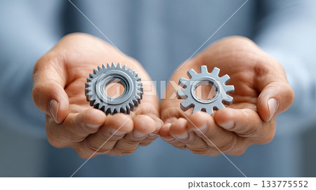 Metal gear wheels held in hands showing mechanical parts 133775552
