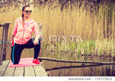 Girl training in sporty clothes on lake shore 133775622