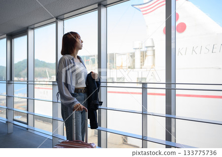 一位年輕的女旅客正從窗戶望著即將啟程的船隻。 一位年輕的女旅客正從窗戶望著即將啟程的船隻。 133775736