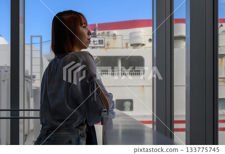 Profile of a young woman looking at a large ferry through the window Profile of a young woman looking at a large ferry through the window 133775745