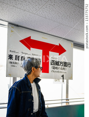 一位白髮老人正望著車站資訊牌前的箭頭方向。 133775752