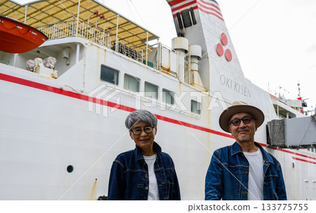 一對中年夫婦，背景是一艘渡輪。 133775755