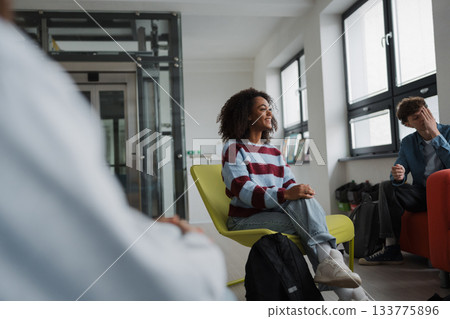 Classmates relaxing and talking in high school lounge. 133775896