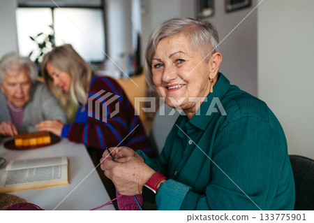 Group of senior people learning knitting together with caregiver tutor in a community center. Group of senior people learning knitting together with caregiver tutor in a community center. 133775901