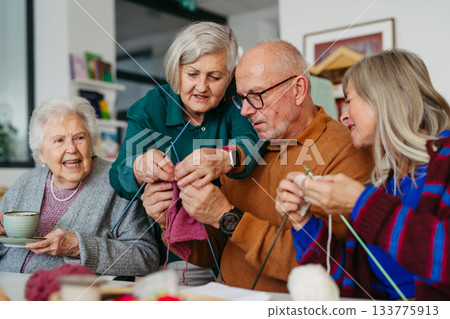 Group of senior people learning knitting together with caregiver tutor in a community center. Group of senior people learning knitting together with caregiver tutor in a community center. 133775913