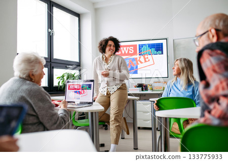 Group of senior people learning digital skills with tutor help. 133775933