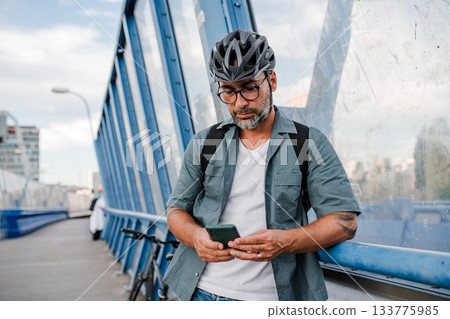 City commuter riding bike from work, reading text message on phone. 133775985