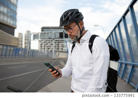 Manager on bike, reading text message on phone. Manager on bike, reading text message on phone. 133775991